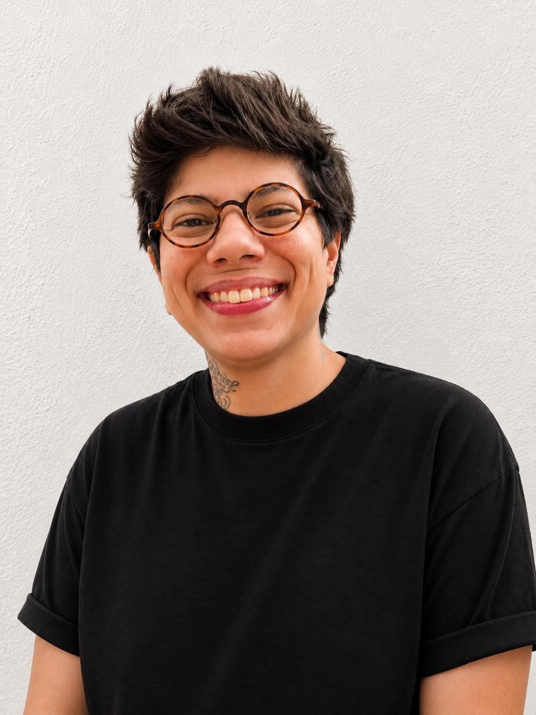 Helena Duppre, de óculos e camiseta preta, sorrindo
